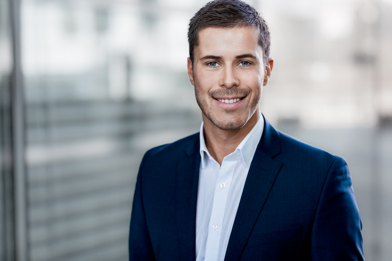 Zeitgemäßes Bewerbungsfoto für Männer in Potsdam: Ausdruck von Symphathie vor minimalistischer Kulisse